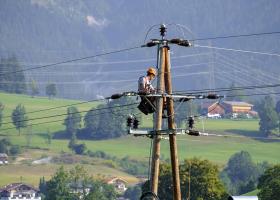 Electricista trabajando en lo alto de un poste de cables de alta tensión