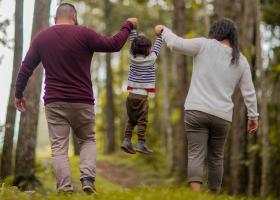 Familia de mamá, papá e hijo caminando en el bosque tomados de la mano