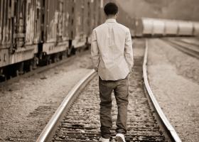 Joven caminando solo sobre las vías de un tren