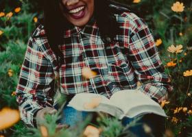 Mujer riendo mientras sostiene un libro en sus manos