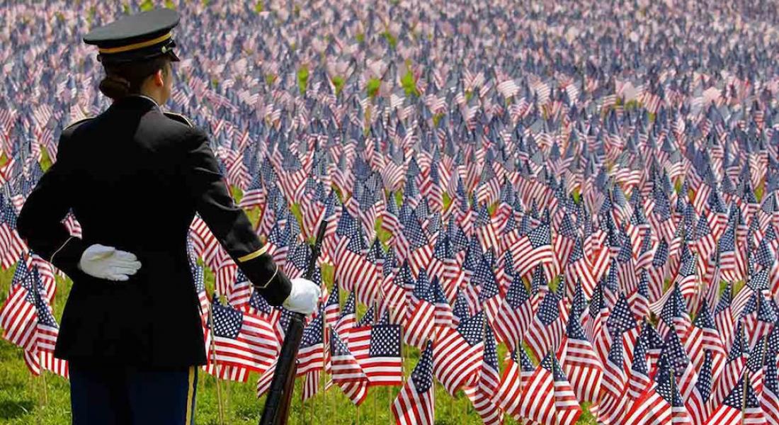 Cadete militar parada frente a cientos de banderas americanas 