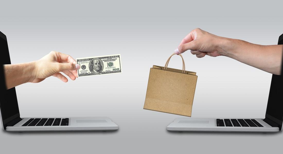 imagen de dos pantallas de computadoras, una frente a la otra, de donde emergen manos humanas intercambiando productos por dinero, ilustrando negocios por internet.
