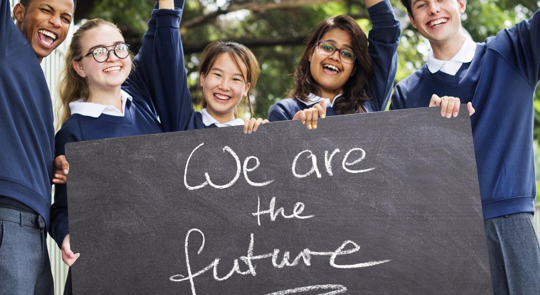 Grupo multicultural de jóvenes estudiantes sosteniendo un cartel que dice: somos el futuro