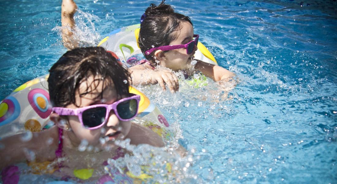 dos niñas nadando con flotador y gafas de sol en una piscina