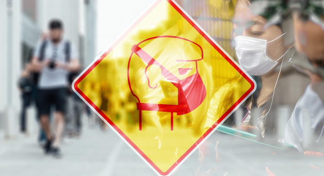 imagen de una señal de advertencia con una persona usando una mascarilla y de fondo una serie de personas en un ambiente citadino